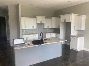 A kitchen with white cabinets and black counter tops.