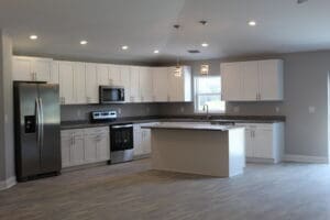 A kitchen with white cabinets and black counter tops.